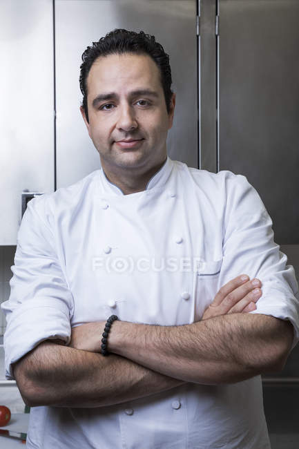 Retrato de chef na cozinha comercial, braços cruzados, olhando para a câmera — Fotografia de Stock