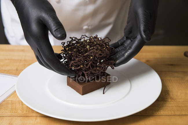 Chef placing chocolate nest cake decoration on cake — Stock Photo