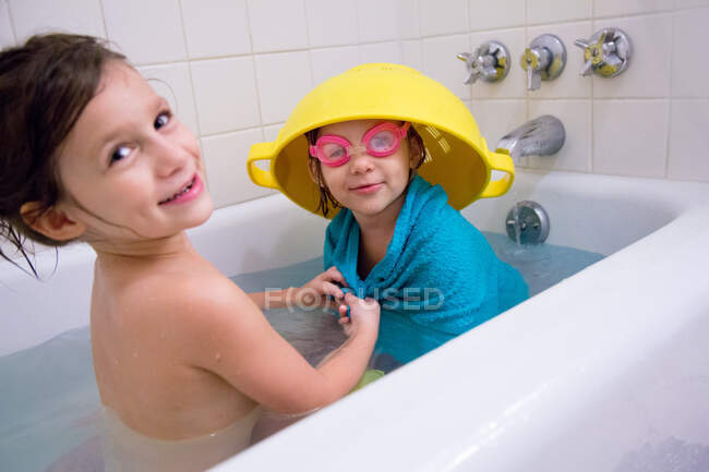Girl having fun dressing up sister in bathtub — Stock Photo