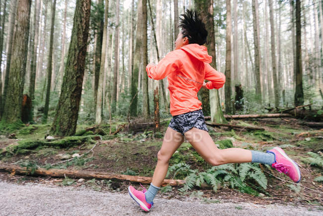 Seitenansicht einer Frau, die im Wald läuft, vancouver, canada — Stockfoto