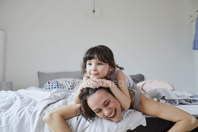 Мать и дочь лежат на кровати в светлой спальне — стоковое фото