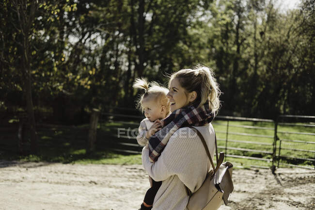 Mother carrying young daughter, in rural setting — Stock Photo