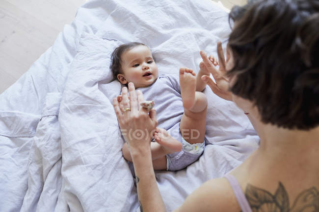 Bebê menina deitada na cama e brincando com a mãe — Fotografia de Stock