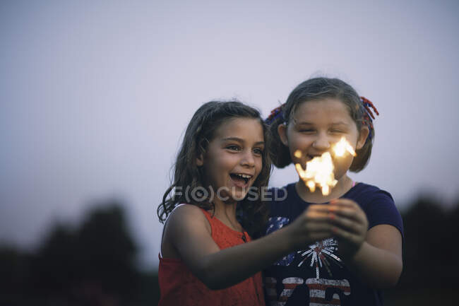 Girls holding sparklers smiling — Stock Photo