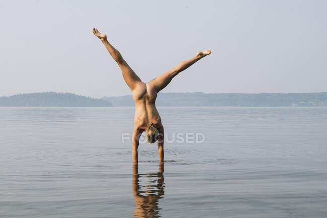 Vista posteriore della donna nuda che fa stand in acqua — Foto stock