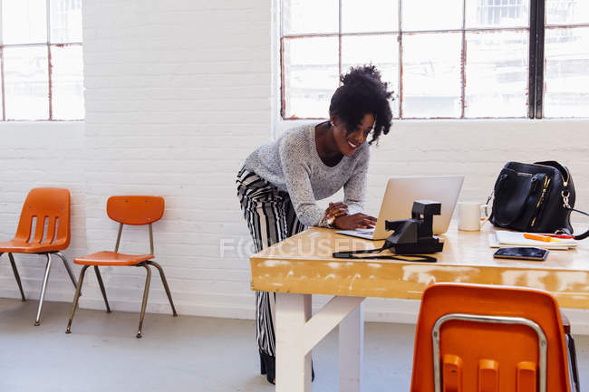 Mulher afro-americana em prédio de escritórios industriais usando laptop — Fotografia de Stock