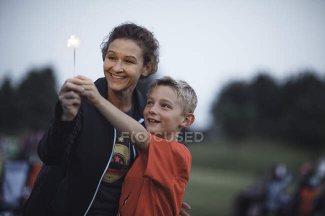 Madre e hijo sosteniendo brillantina sonriendo - foto de stock