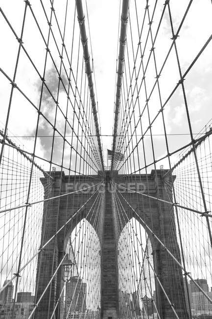 View of Brooklyn Bridge and American flag, B & W, New York, USA — стоковое фото