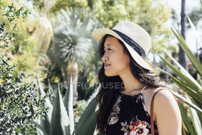 Jovem mulher ao ar livre, olhando para as plantas no jardim — Fotografia de Stock