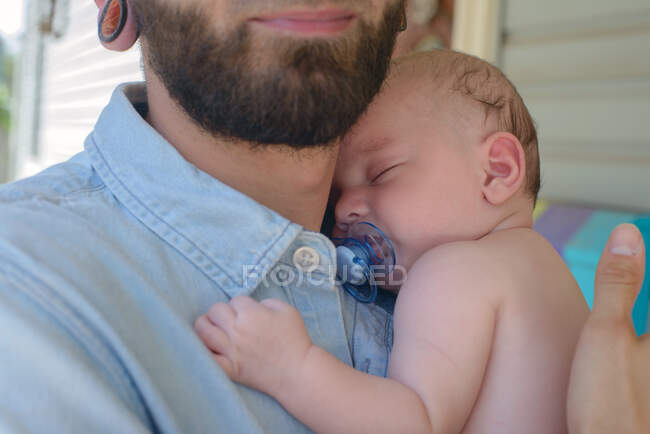 Мужчина со спящим мальчиком на плече — стоковое фото