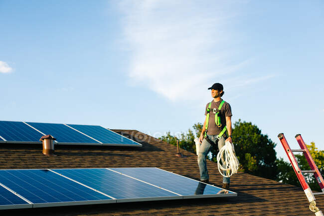 Trabajador de pie en el techo de la casa, la instalación de paneles solares - foto de stock