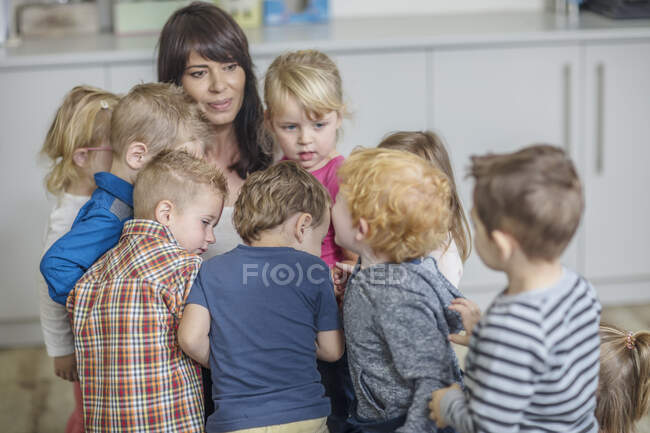 Ciudad del Cabo, Sudáfrica, niños pequeños en el aula de pie alrededor de su maestro - foto de stock