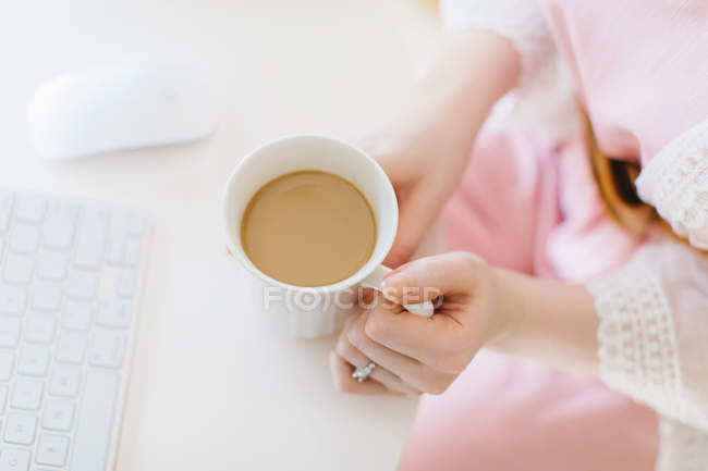 Jovem sentada no computador com caneca de café — Fotografia de Stock