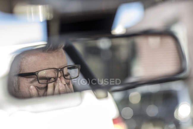 Ciudad del Cabo, Sudáfrica, reflejo en el espejo retrovisor de un hombre frotándose los ojos - foto de stock
