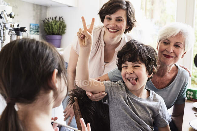 Young girl photographing, brother, mother and grandmother, using smartphone — Stock Photo