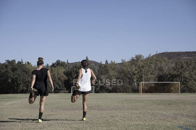 Жінки розтягують ноги на футбольному полі — стокове фото