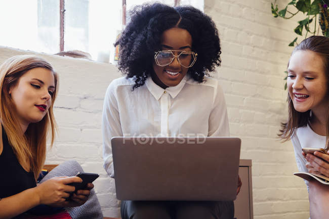 Front view of Colleagues sitting together on sofa in office using laptop — Stock Photo