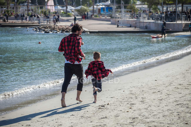 Vater und Sohn rennen am Strand entlang — Stockfoto