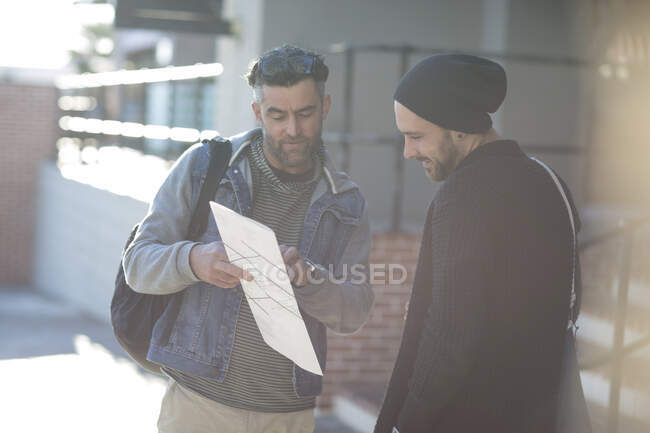 Two men in street, looking at map — Stock Photo