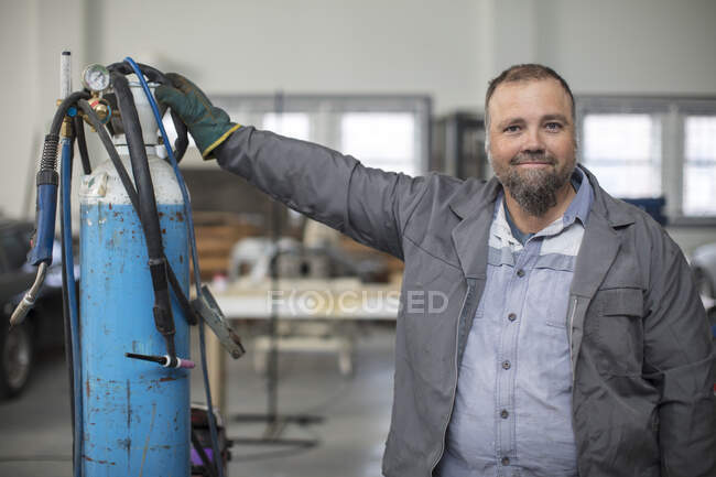 Retrato de mecánico de coche macho maduro en garaje de reparación - foto de stock