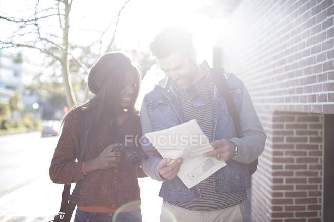 Man and woman with map and camera outdoors — Stock Photo