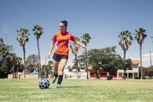 Studentessa adolescente calci pallone da calcio sul campo sportivo della scuola — Foto stock
