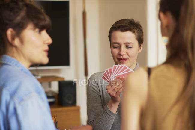 Три друзі-жінки грають в карти у вітальні — стокове фото