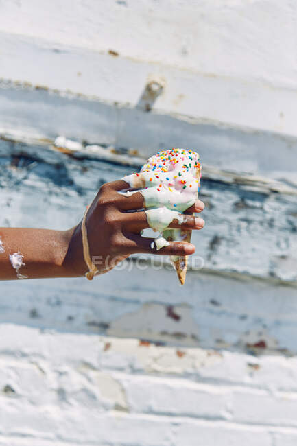 Donna che tiene lo scioglimento, gocciolante cono gelato, primo piano di mano — Foto stock