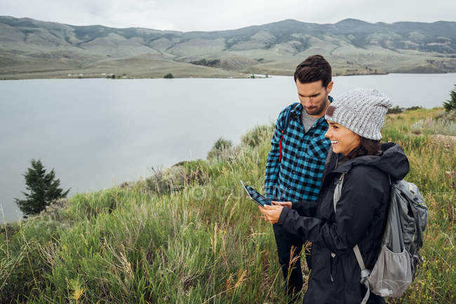 Coppia in piedi accanto a Dillon Reservoir, utilizzando tablet digitale, Silverthorne, Colorado, USA — Foto stock
