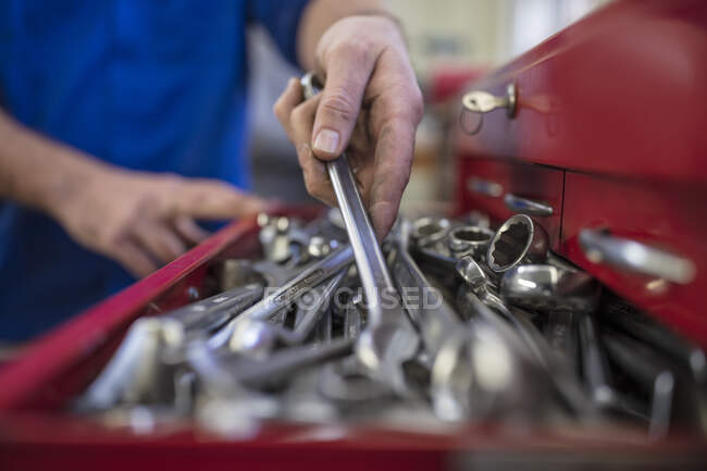 Manos del mecánico masculino del coche que selecciona la llave de la caja de herramientas en el garaje de reparación - foto de stock