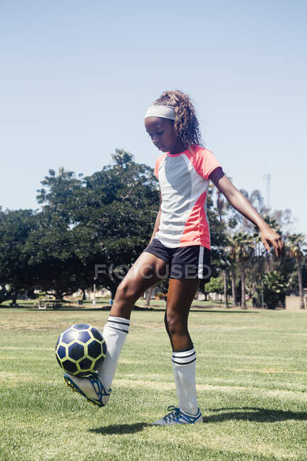 Школярка-підліток практикує тривалий час з футбольним м'ячем на шкільному спортивному полі — стокове фото