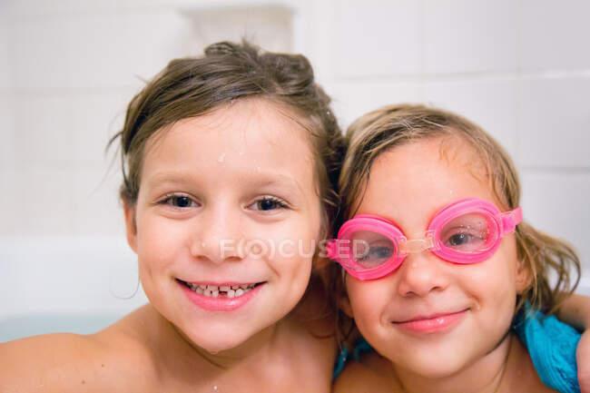 Portrait of sisters in bath looking at camera smiling — Stock Photo
