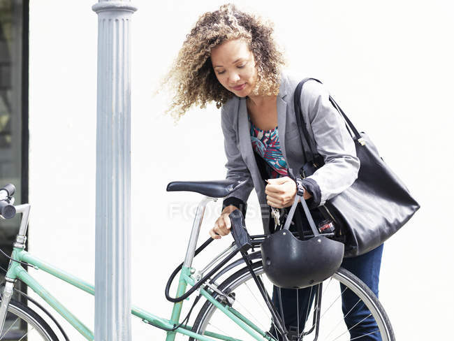 Mid adult woman securing bicycle after journey — Stock Photo