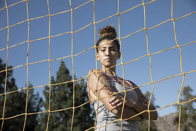 Portrait of woman behind football goal netting looking at camera — Stock Photo