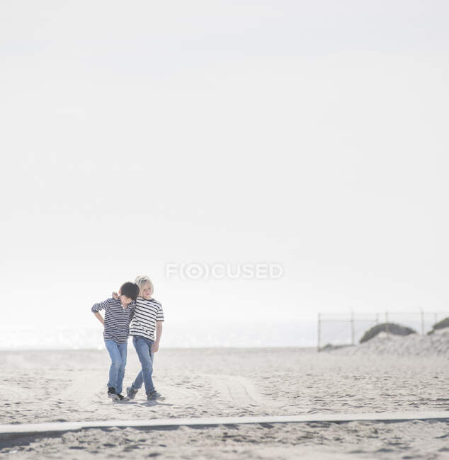 Мальчики гуляют по песчаному пляжу — стоковое фото