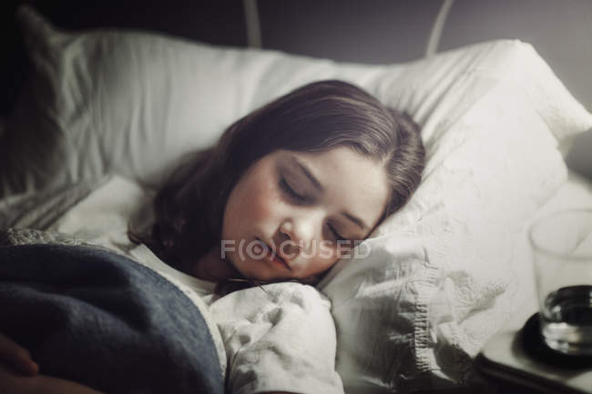 Портрет девушки, спящей в постели, спящей с включенным светом — стоковое фото