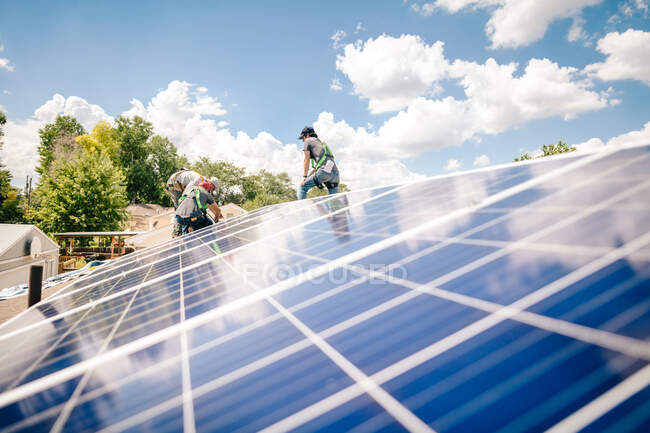 Trabajadores instalando paneles solares en el techo de la casa, vista de ángulo bajo - foto de stock
