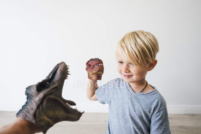 Niño y padre jugando con títeres de mano de dinosaurio - foto de stock