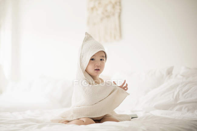 Мальчик с капюшоном и полотенцем в постели — стоковое фото