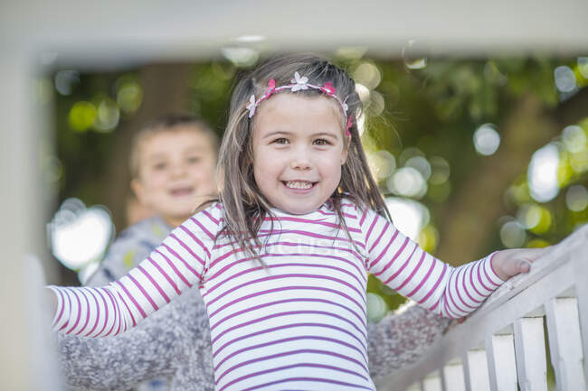 Mädchen und Junge im Kindergarten, Porträt auf Klettergerüst im Garten — Stockfoto