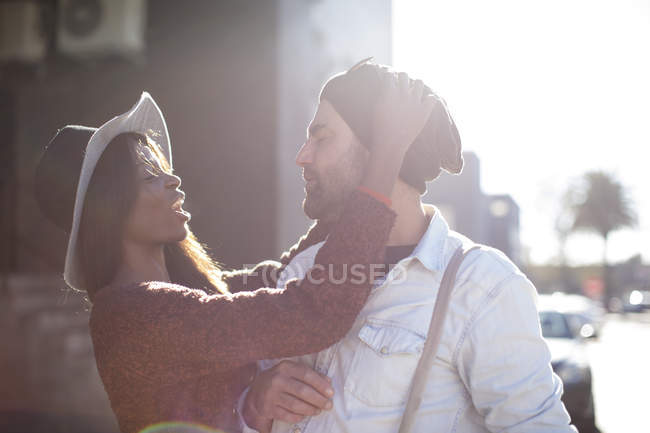 Woman putting knitted hat on man outdoors — Stock Photo