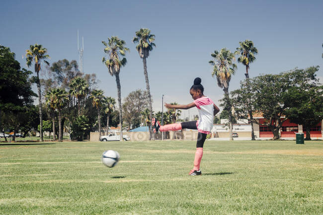 Estudante chutando bola de futebol no campo de esportes da escola — Fotografia de Stock