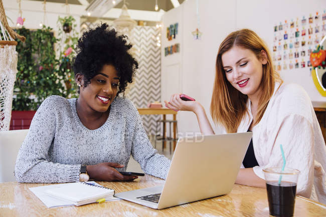 Щасливі усміхнені жінки Колеги в офісі використовують ноутбук за столом — стокове фото
