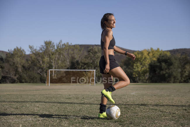 Giovane donna sul campo da calcio giocare a calcio — Foto stock