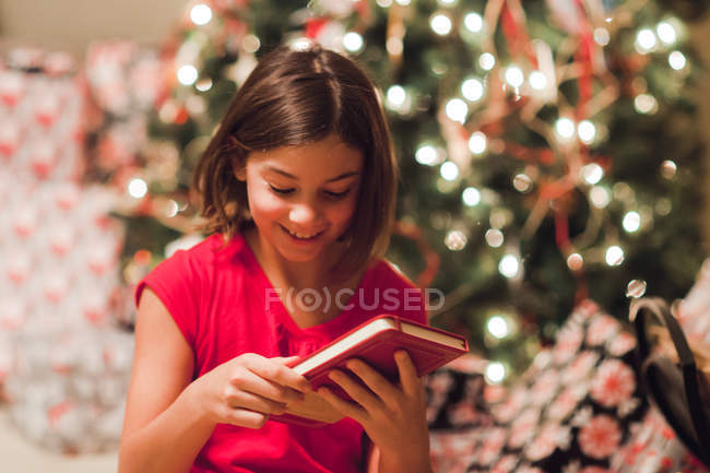 Chica sonriente desenvolviendo regalo de Navidad - foto de stock