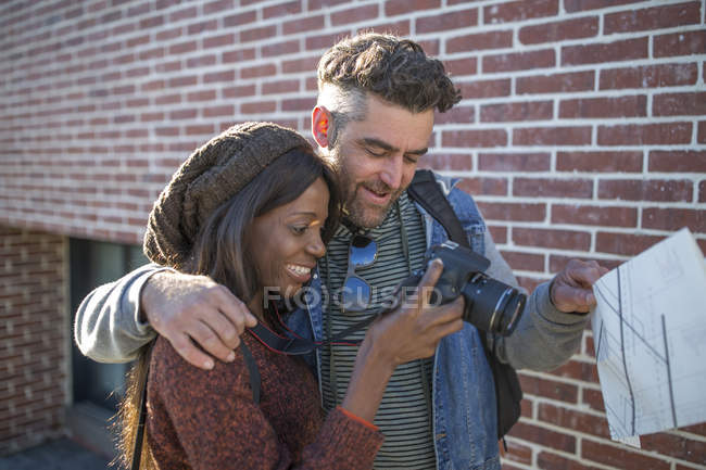 Paar blickt auf die Rückseite der Digitalkamera und lächelt — Stockfoto