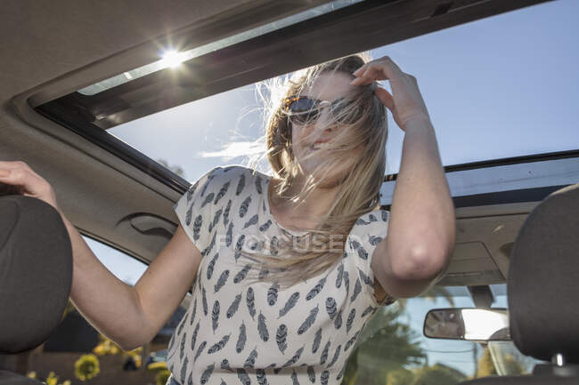 Ciudad del Cabo, Sudáfrica, joven mujer mirando a través del techo corredizo del coche - foto de stock