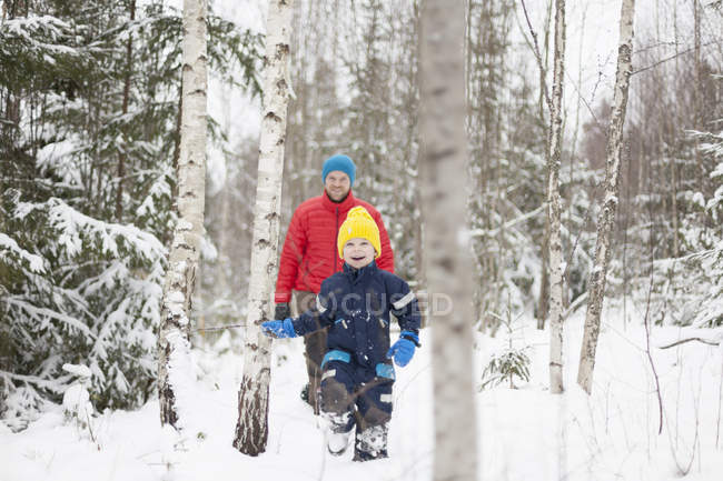 Man and son walking in snow covered forest — Stock Photo