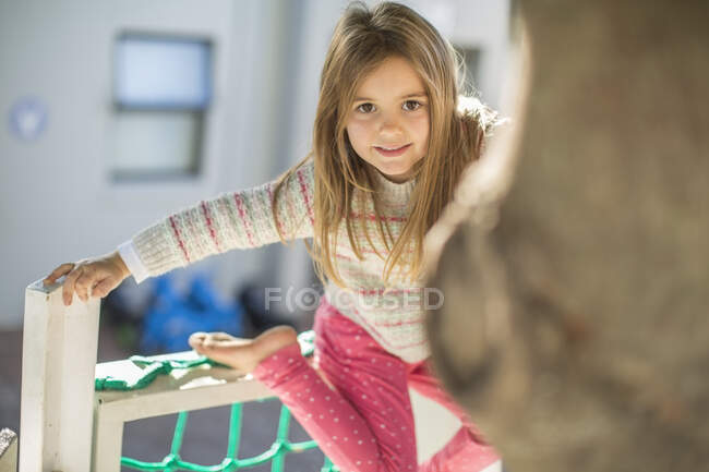 Niña en preescolar, retrato en el marco de escalada en el jardín - foto de stock