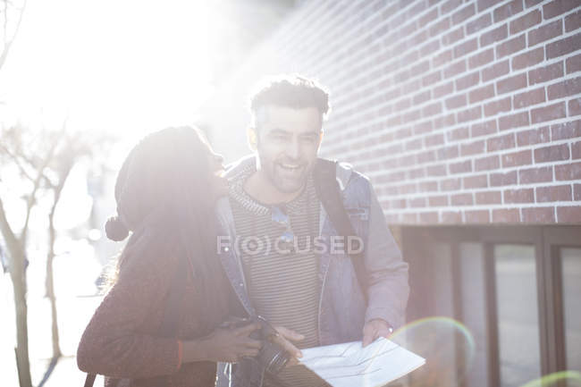 Мужчина и женщина с картой и камерой смеются на улице — стоковое фото
